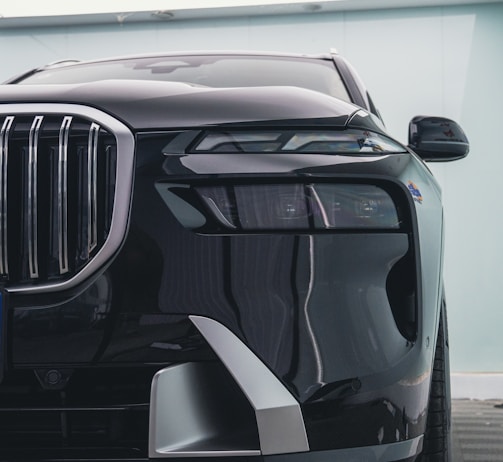 Close-up of a shiny black luxury sedan’s front grille and headlights.