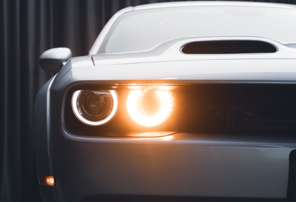 a close up of the headlights of a white sports car