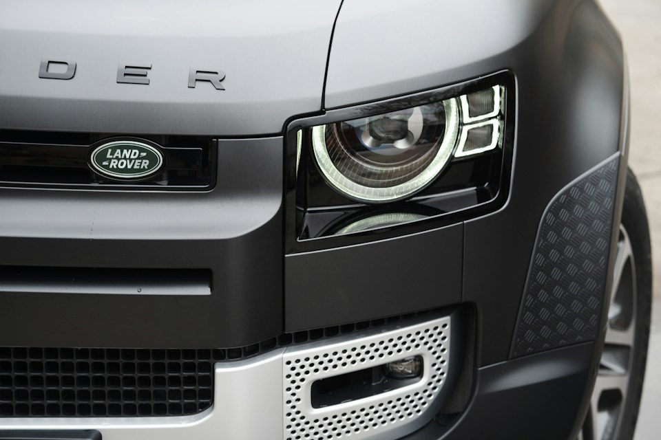Close-up of a clear LED headlight on a gray Land Rover Defender showcasing headlight restoration results