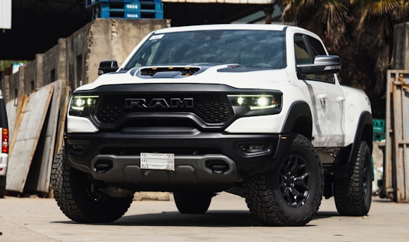 A sleek Ram 3500 pickup truck hooked to a 40ft gooseneck trailer parked on an industrial highway.
