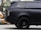 A sleek black SUV with tinted windows, featuring a modern and luxurious design. The focus is on the rear side and the distinctive alloy wheels, while the background is slightly blurred, indicating an urban setting.