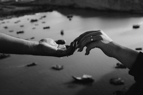 a couple of people holding hands over a body of water