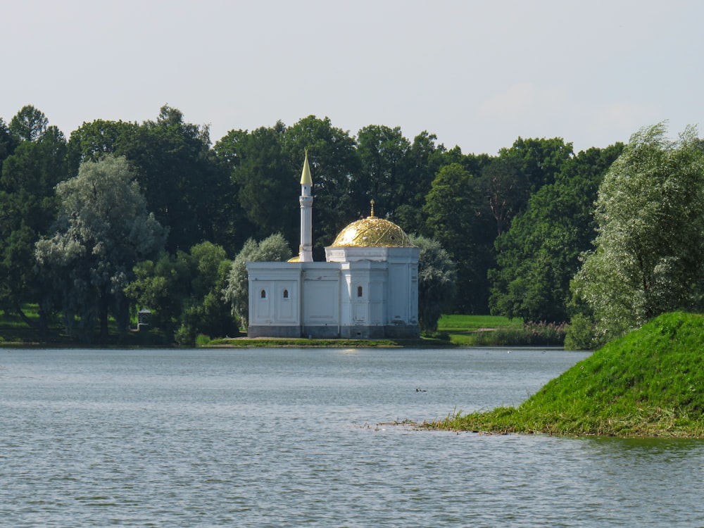 a white building with a golden dome sitting on top of a lake