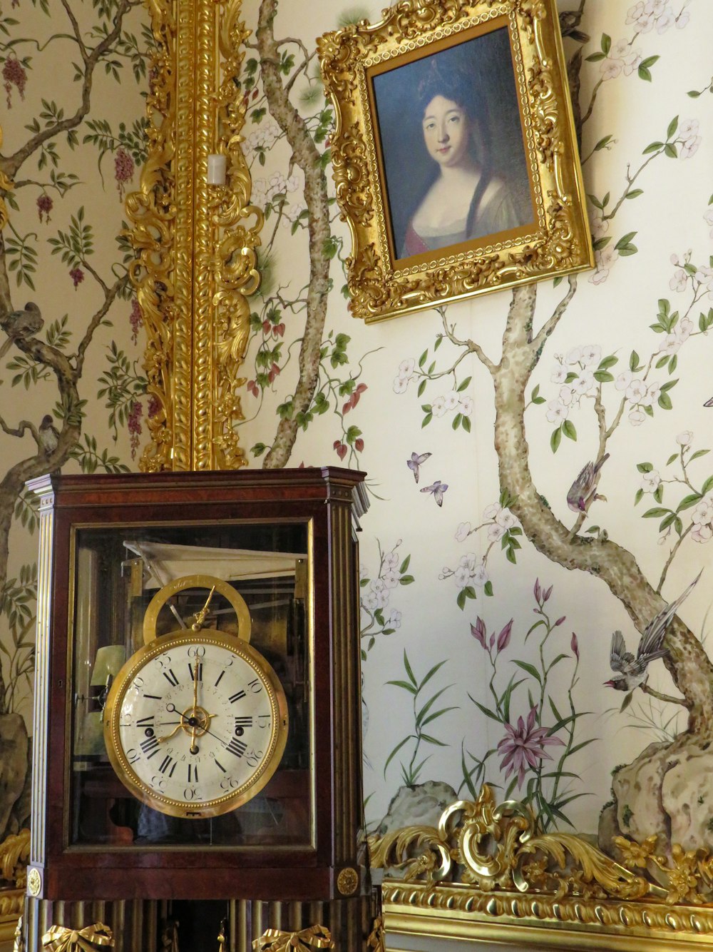 a clock sitting on top of a table next to a painting