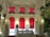 A luxurious, ornately decorated interior with rich red curtains draping down from large windows. The intricate white moldings and carvings adorn the walls and ceiling, creating an elegant and opulent atmosphere. A grand staircase lined with decorative vases and lighting leads to the upper level. Abundant floral arrangements add a touch of nature to the sophisticated setting.