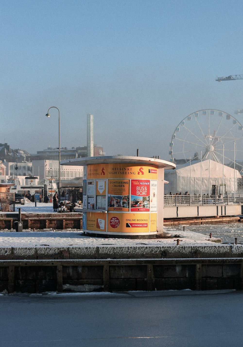 a yellow box sitting on top of a pier next to a ferris wheel