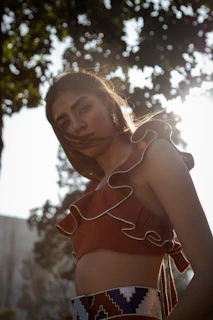 A young woman applying Genelix sunscreen outdoors with sunlight filtering through trees