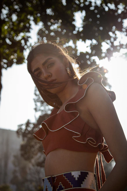 A young woman applying Genelix sunscreen outdoors with sunlight filtering through trees
