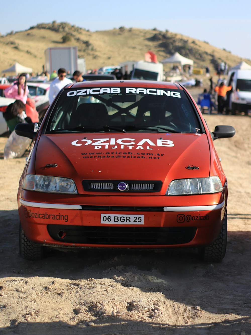 a red car parked on top of a dirt field