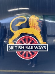 A logo featuring a stylized yellow lion standing leftward on a circular red wheel. Below the lion, the words 'British Railways' are prominently displayed on a black background.
