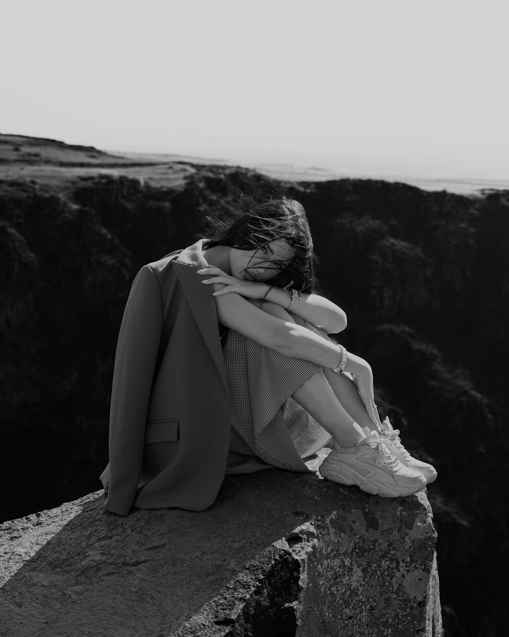 a woman sitting on top of a cliff next to the ocean