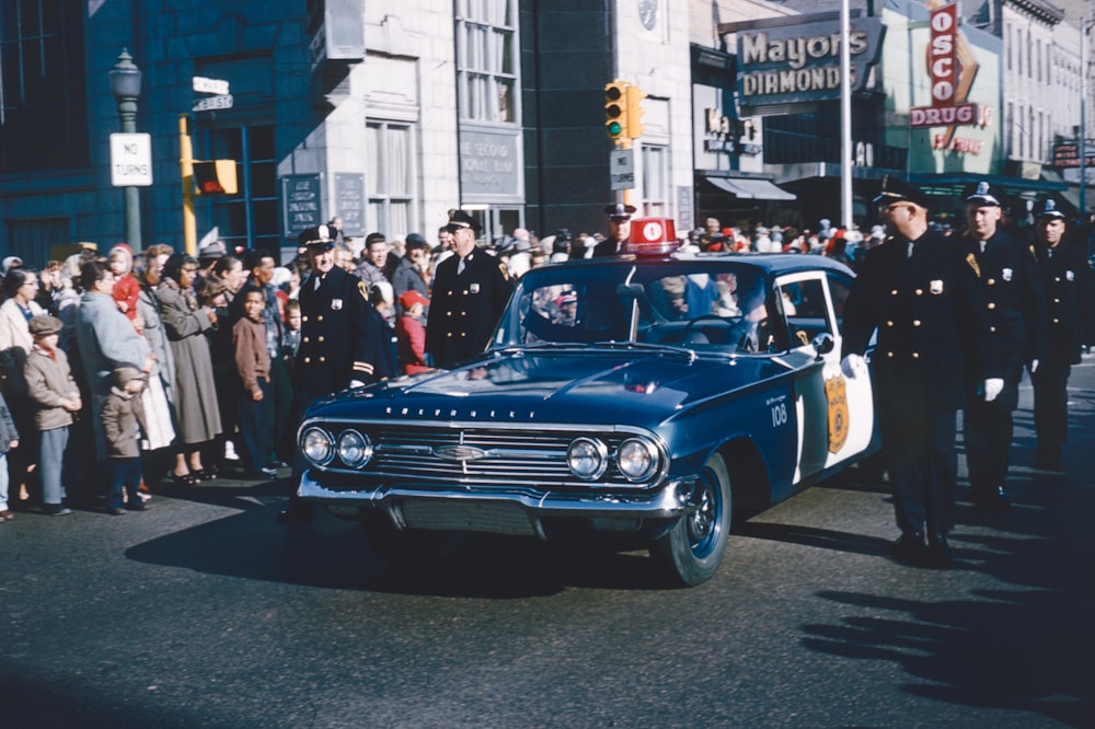 a police car driving past a crowd of people