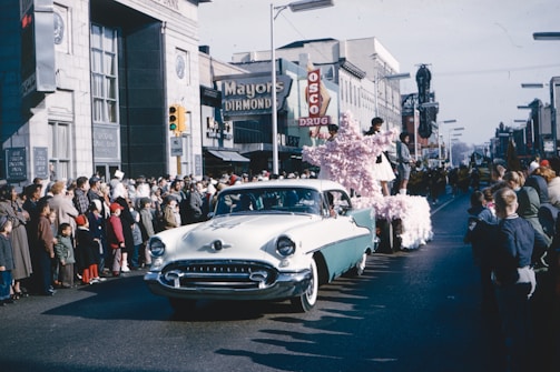 A vintage car parade winding through the main street with cheering crowds.