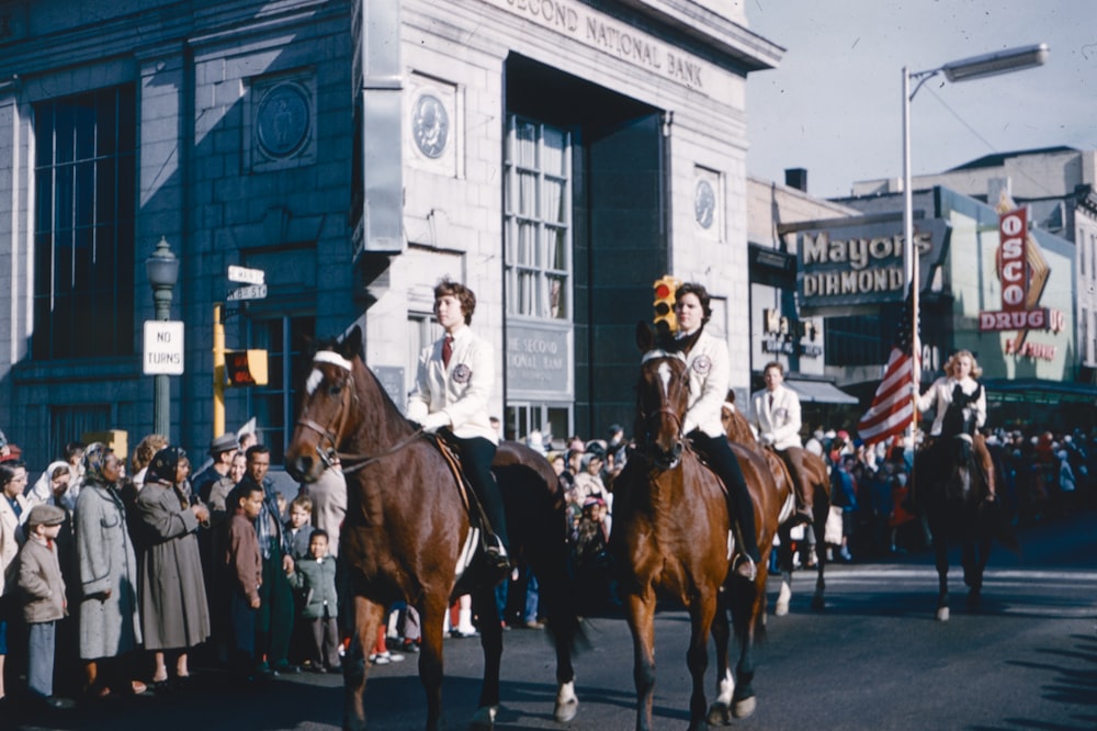 a group of people riding horses down a street