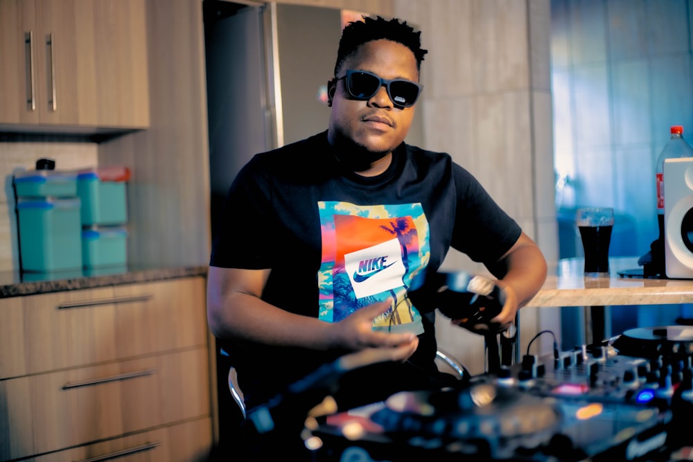 a man in a black shirt and sunglasses mixing music