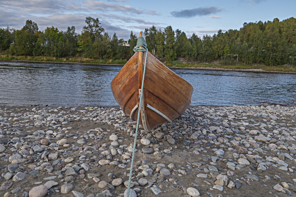 a wooden boat sitting on top of a rocky beach