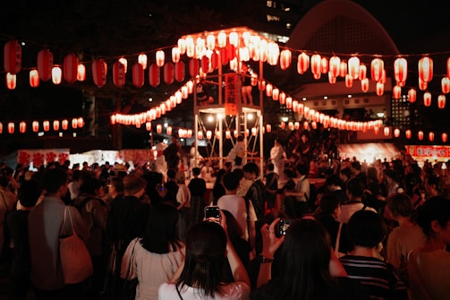 A lively street festival with dancers and lanterns at night.