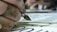 A close-up of a student practicing elegant calligraphy strokes with a dip pen.