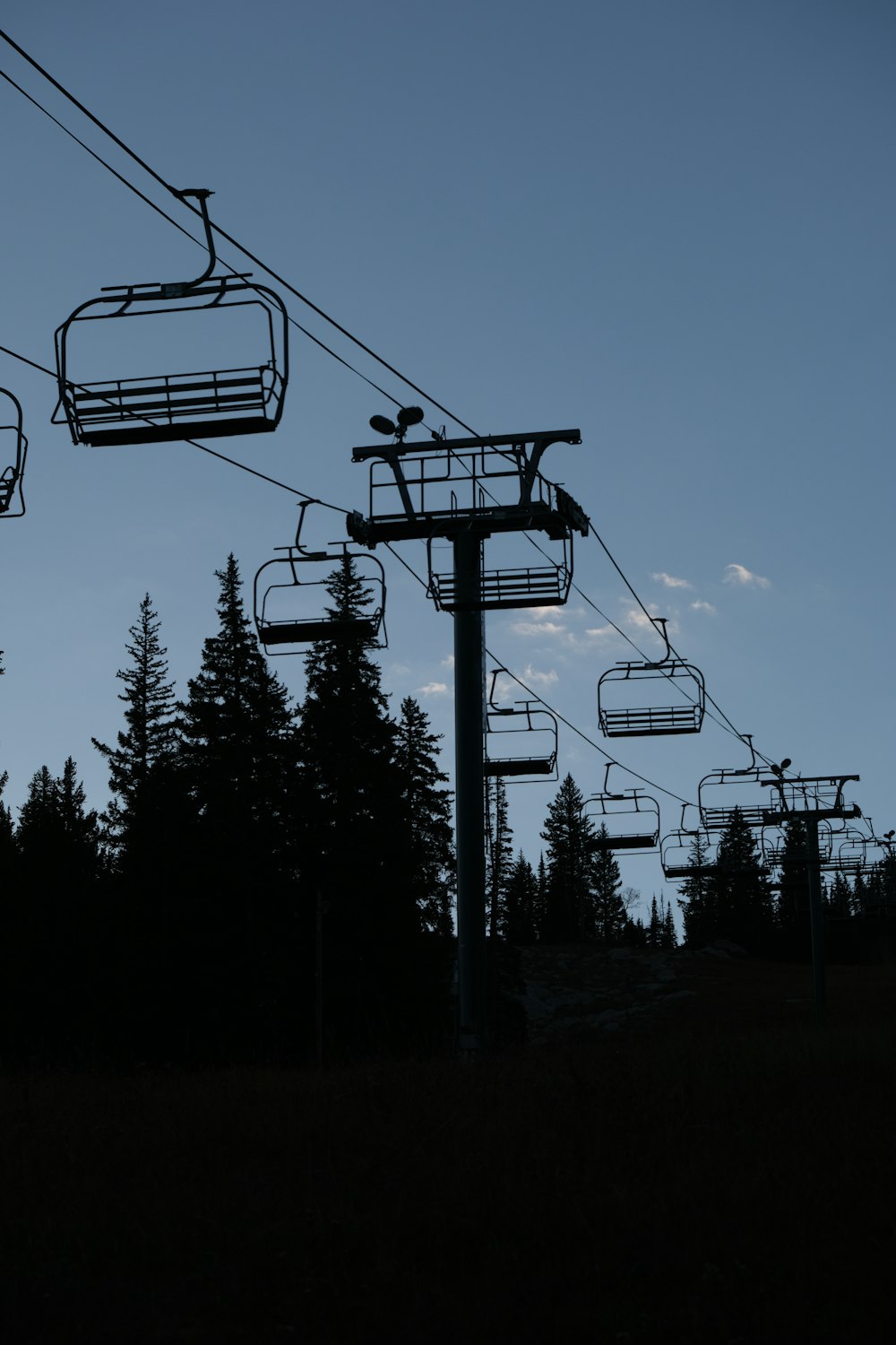 a ski lift going up a hill with trees in the background