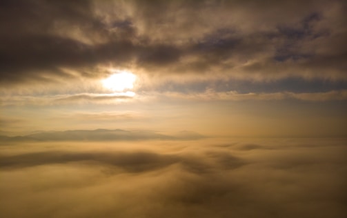 Close-up of golden sun rays piercing through a misty morning sky.