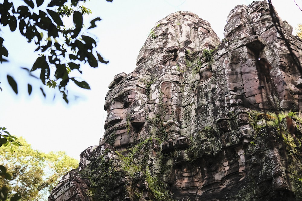 a group of faces on the side of a rock formation