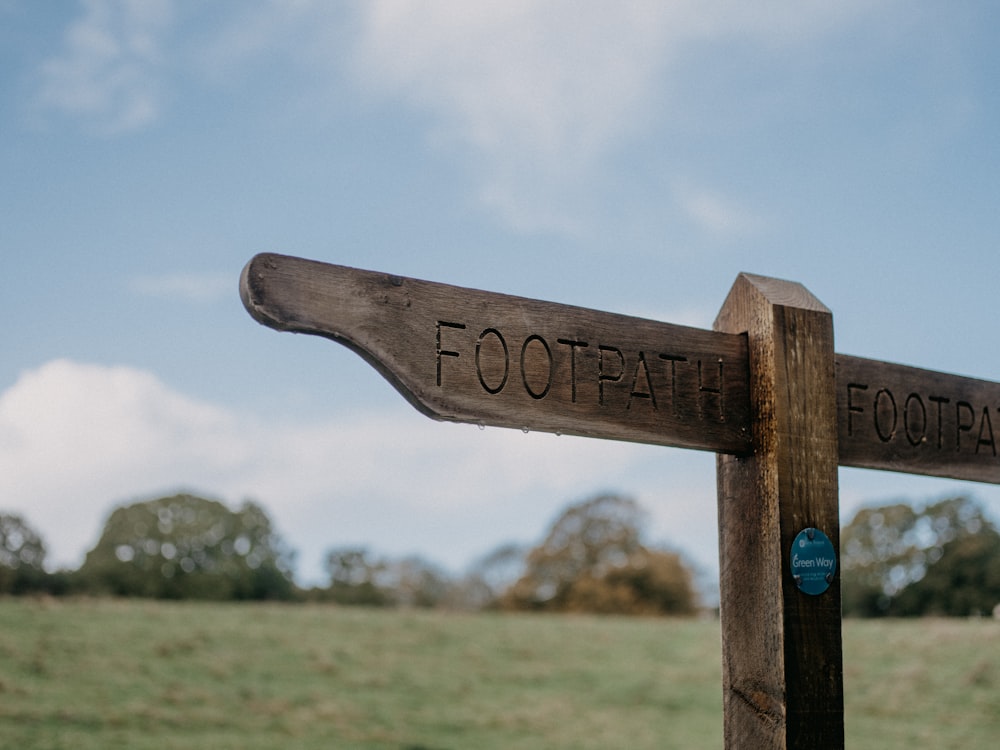 a close up of a wooden sign with a field in the background