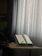 A peaceful room with soft natural light and spiritual books on a wooden shelf.