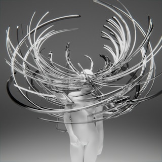 A minimalistic white humanoid figure is surrounded by an intricate array of swirling, elongated metallic and transparent structures, creating a dynamic and abstract visual effect. The background is a plain gradient gray, which enhances the focus on the central figure and the surrounding elements.