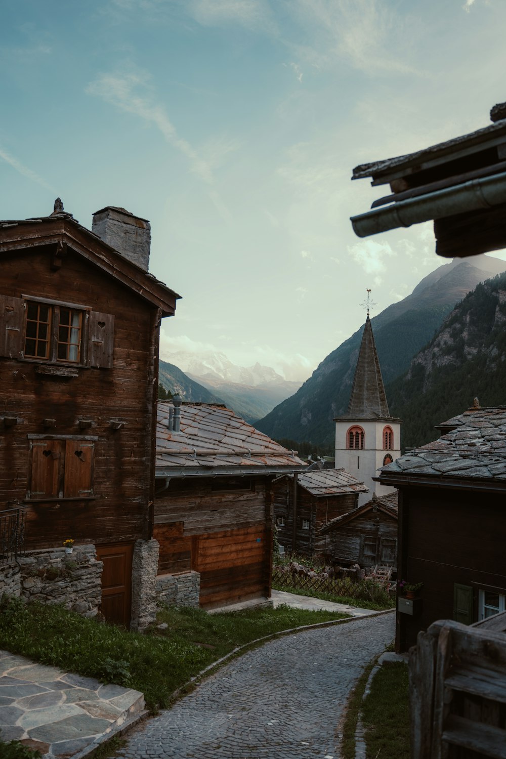 a cobblestone road leading to a wooden building with a steeple in the