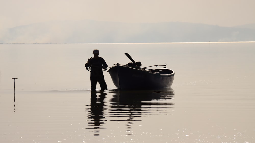 a man standing in the water next to a boat