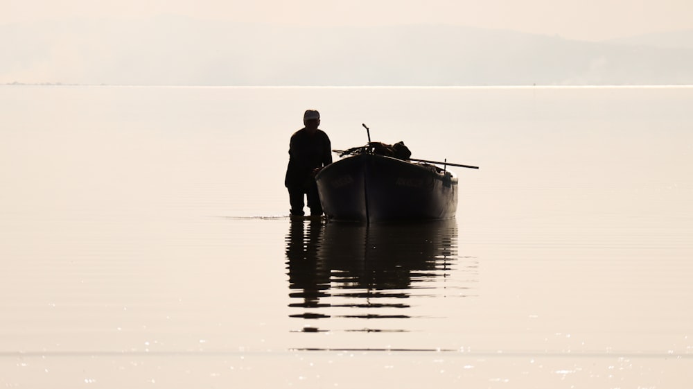 a man standing in the water next to a boat