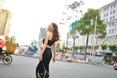 Woman carrying a stylish leather purse walking through a bustling city street.