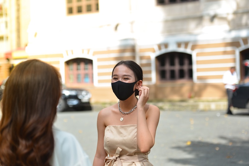 Stylish woman on phone in designer mask