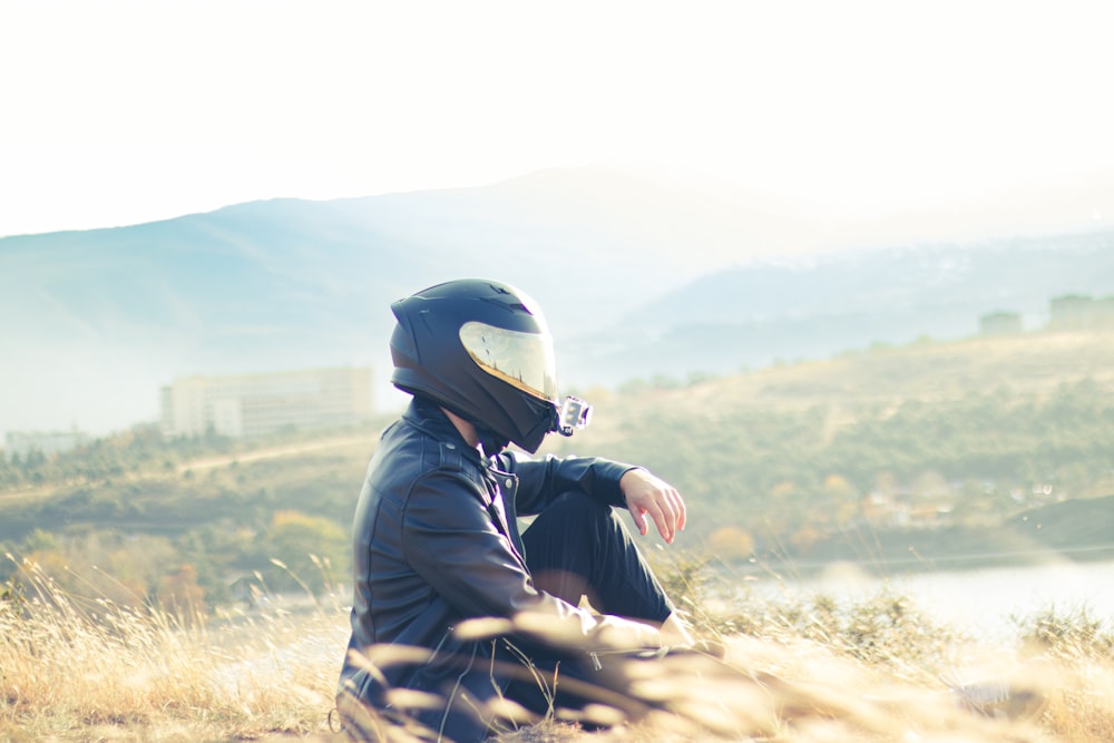 a person sitting on a hill with a motorcycle helmet on
