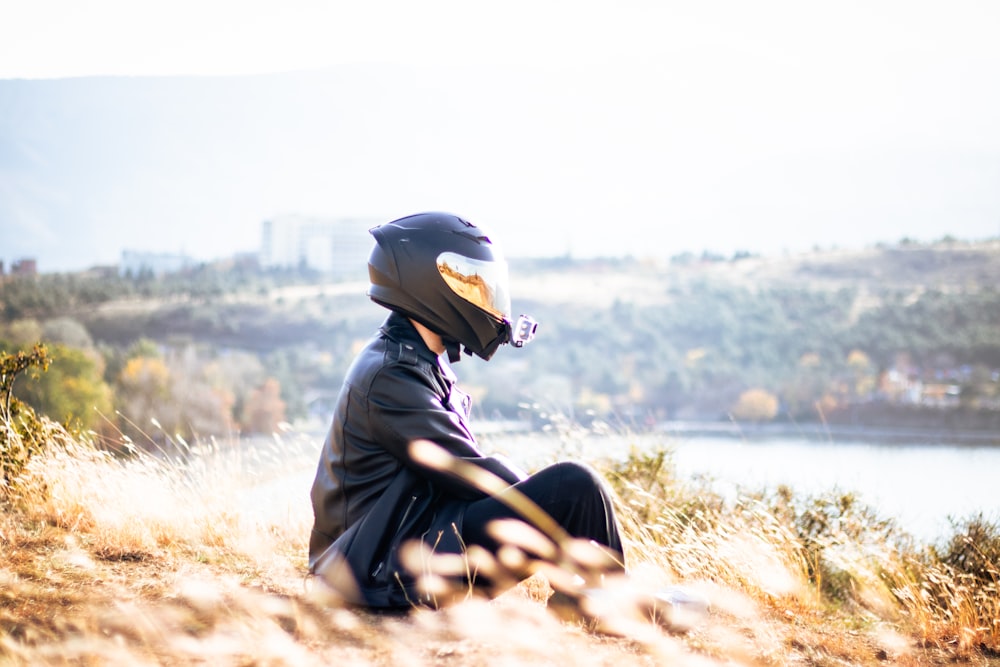 a person sitting on a hill with a helmet on