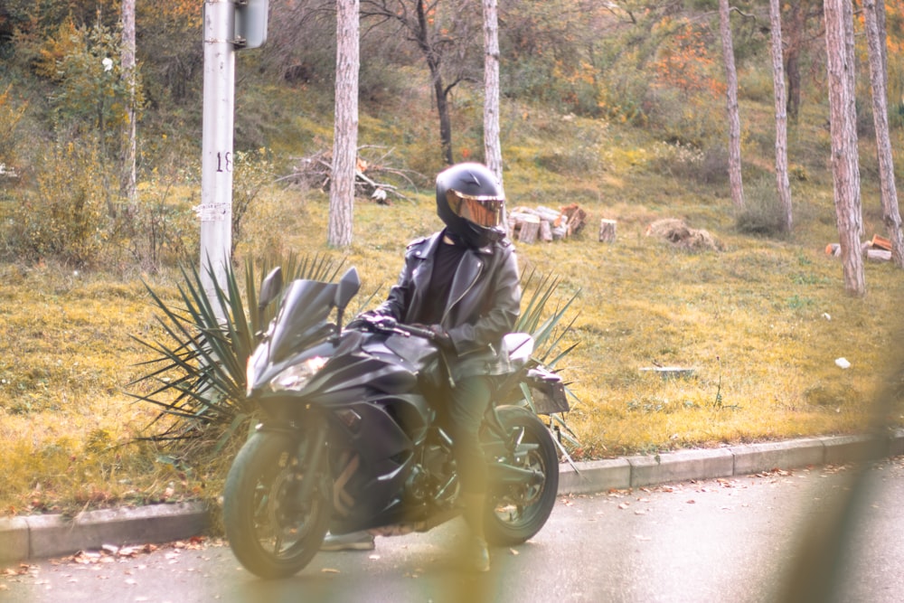 a man riding a motorcycle down a street next to a forest