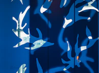 Abstract wall art with playful leaf shapes in bold colors on a rustic wooden background.