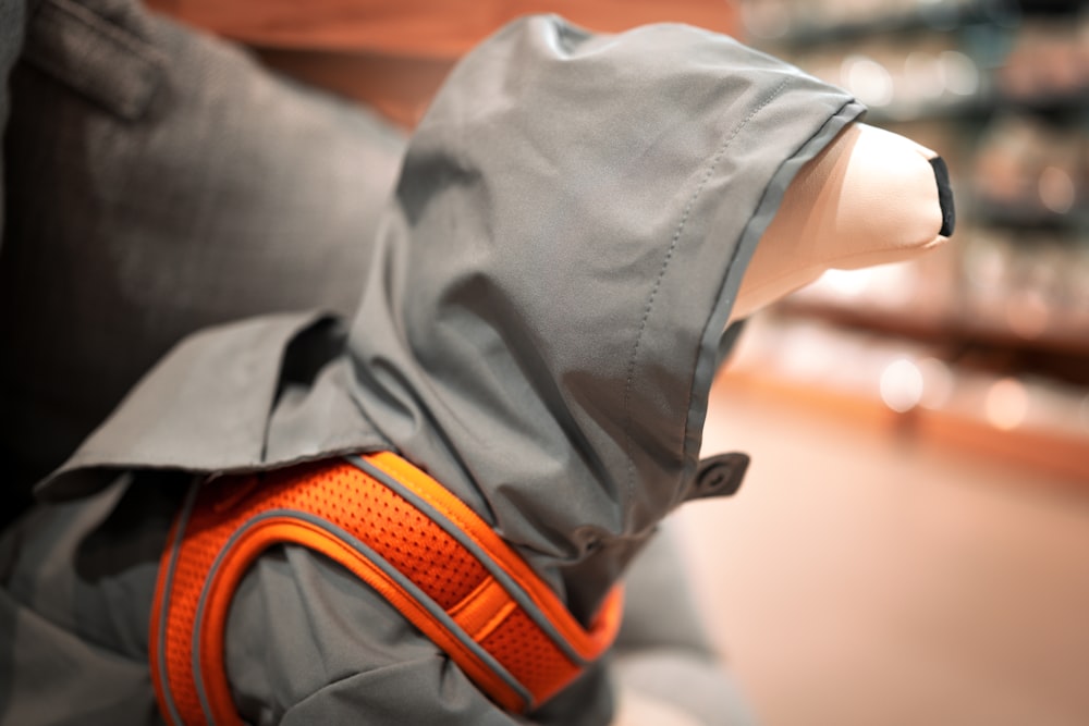 a mannequin wearing a gray jacket and orange harness