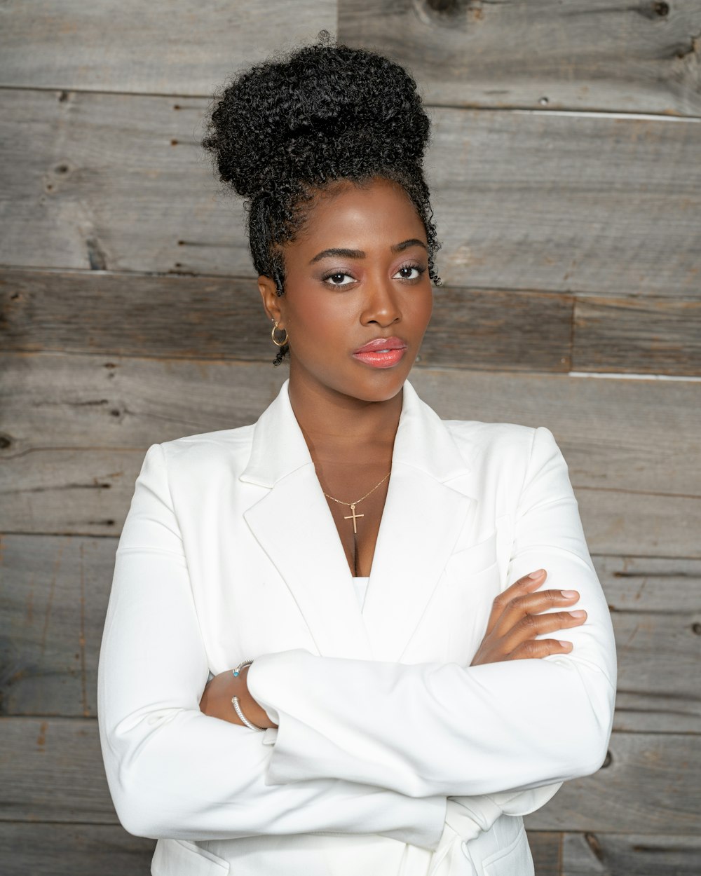 a woman in a white suit standing with her arms crossed