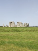Tour group exploring the ancient stones of Stonehenge under a clear blue sky.