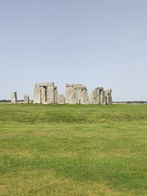 Tour group exploring the ancient stones of Stonehenge under a clear blue sky.