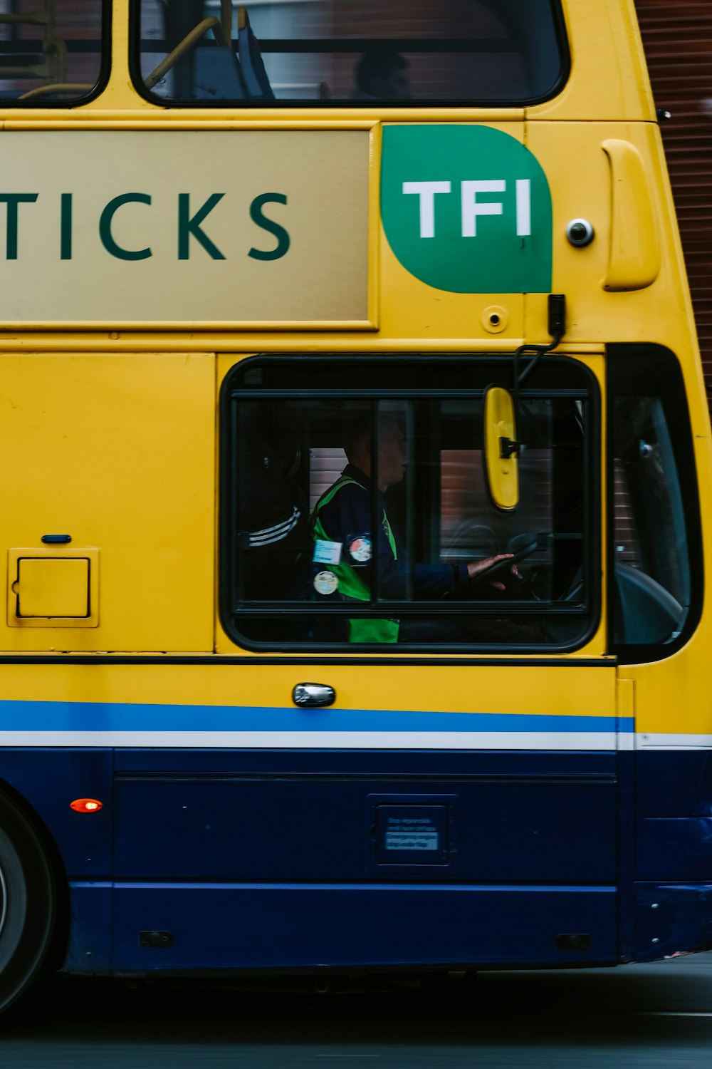 a yellow and blue double decker bus driving down a street