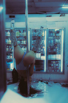 A woman joyfully practicing pole dance in a sunlit studio.