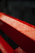 a red bench with water drops on it