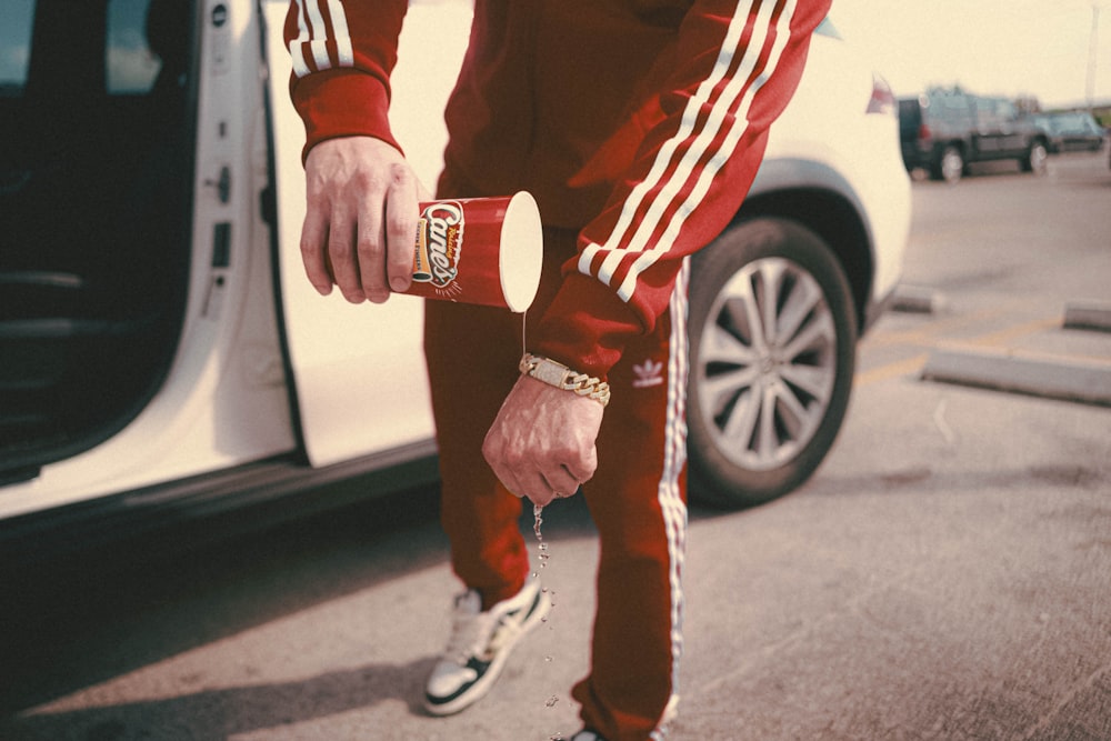 a man in a red track suit holding a skateboard