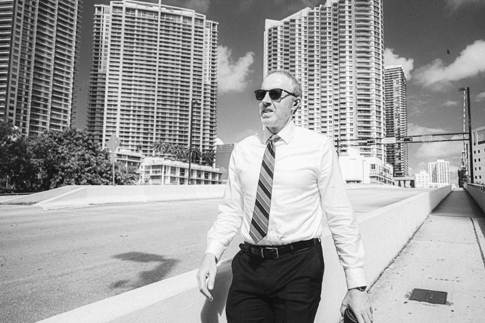 a man in a tie and sunglasses walking down the street