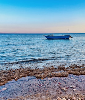 A calm morning scene with soft sandy neutrals and the boat anchored near a coral reef.