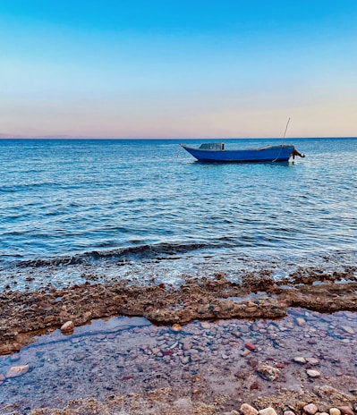 A calm morning scene with soft sandy neutrals and the boat anchored near a coral reef.