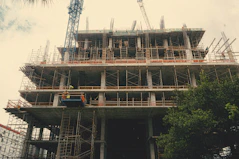 Construction workers collaborating on site, surrounded by steel frameworks and cranes.