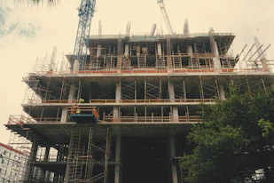Modern construction site with cranes and workers building a multi-story building.